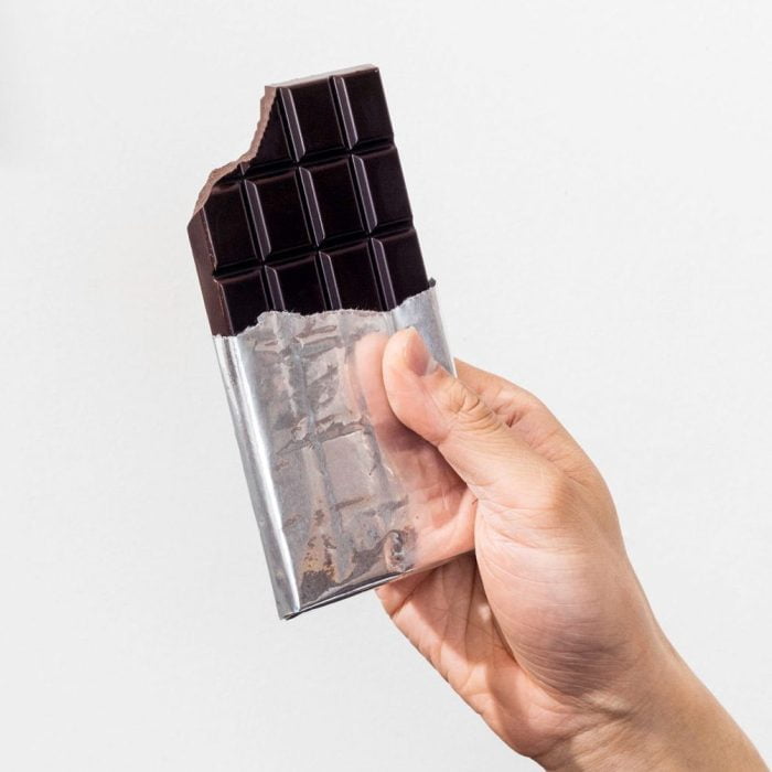 Hand holding up a Mr. Funguy Vegan Dark Milk Chocolate Bar with aluminum foil on the bottom